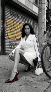 fashion model in white blazer dress sitting through urban street with graffiti background
